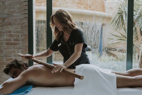 A massage therapy session in a room with a brick wall and a large window overlooking a waterfall. - Hotel La Laguna Spa And Golf (Rojales)