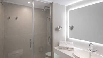 A modern bathroom with a glass-enclosed shower, a white sink, and a large mirror.