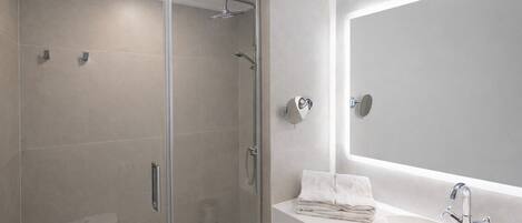 A modern bathroom with a glass-enclosed shower, a white sink, and a large mirror.