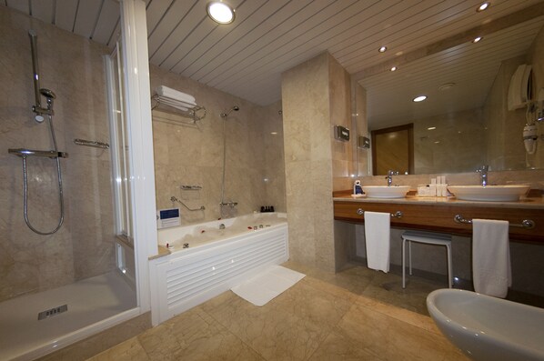 A modern bathroom with a walk-in shower, a freestanding bathtub, a vanity with a double sink, and a large mirror.