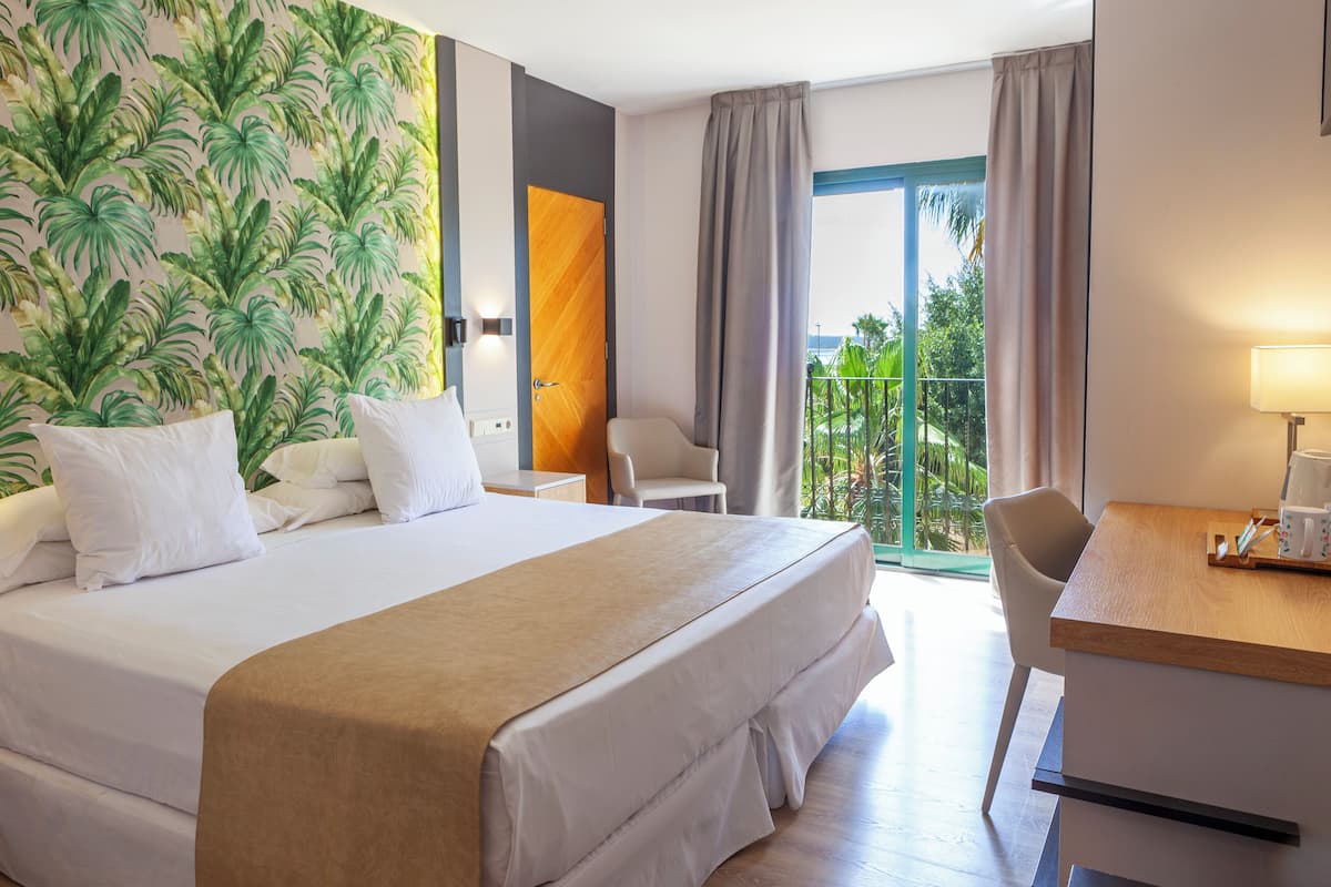 A hotel room with a large bed, a desk, and a view of the outdoors.