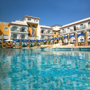 Relax by the pool surrounded by lush greenery and arched windows.