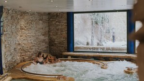 A hot tub area with stone walls and a view of a waterfall outside. - Hotel La Laguna Spa And Golf (Rojales)