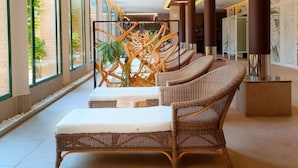 Un vestíbulo moderno con mobiliario de mimbre, amplias ventanas y elementos decorativos de madera.