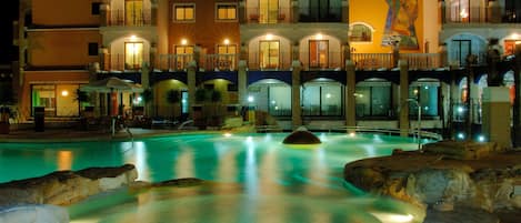 Un hotel con varios balcones, piscina y un mural en la fachada del edificio.