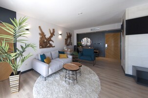 Una sala de estar moderna con un sofá, una mesa de centro y arte decorativo en la pared.