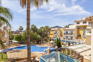Relax by the resort's central pool surrounded by shaded lounge areas with umbrellas.