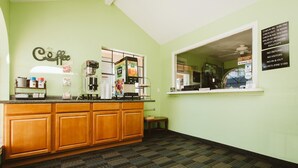 Una cocina con estación de café, un cartel con horarios de registro de entrada y salida, y una ventana con vistas.