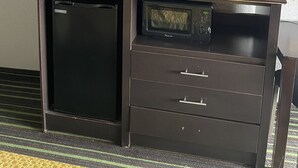 Un minibar compacto con un televisor encima, un refrigerador pequeño y un microondas.