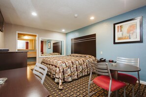 A hotel room with a bed, a desk, a chair, and a table.
