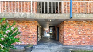 A corridor with brick walls, a concrete floor, and a metal railing on the upper level. - Hahira Inn By OYO near Valdosta (Hahira)