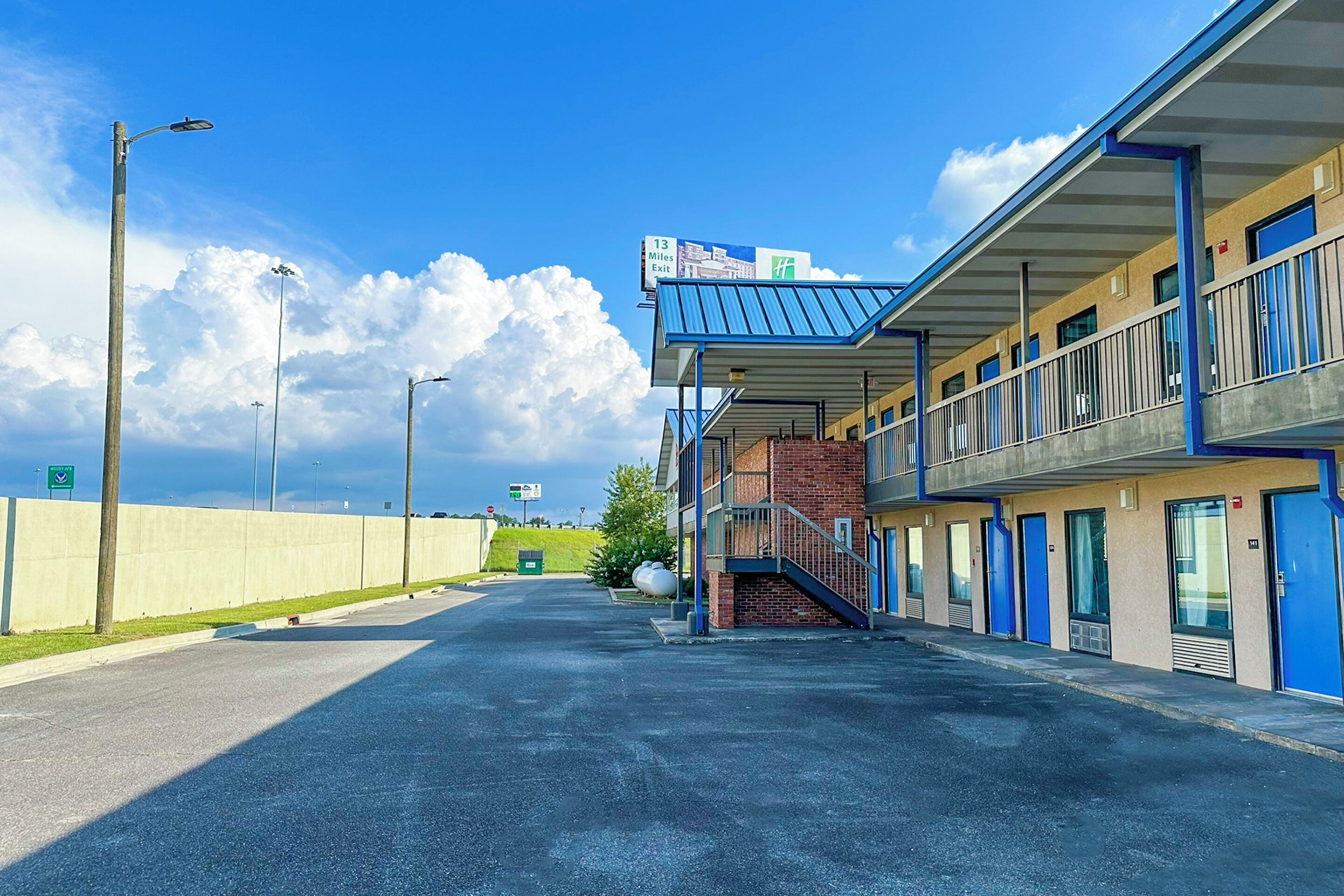 A motel with a covered outdoor area, a clear sky, and a sign indicating the distance to the exit.