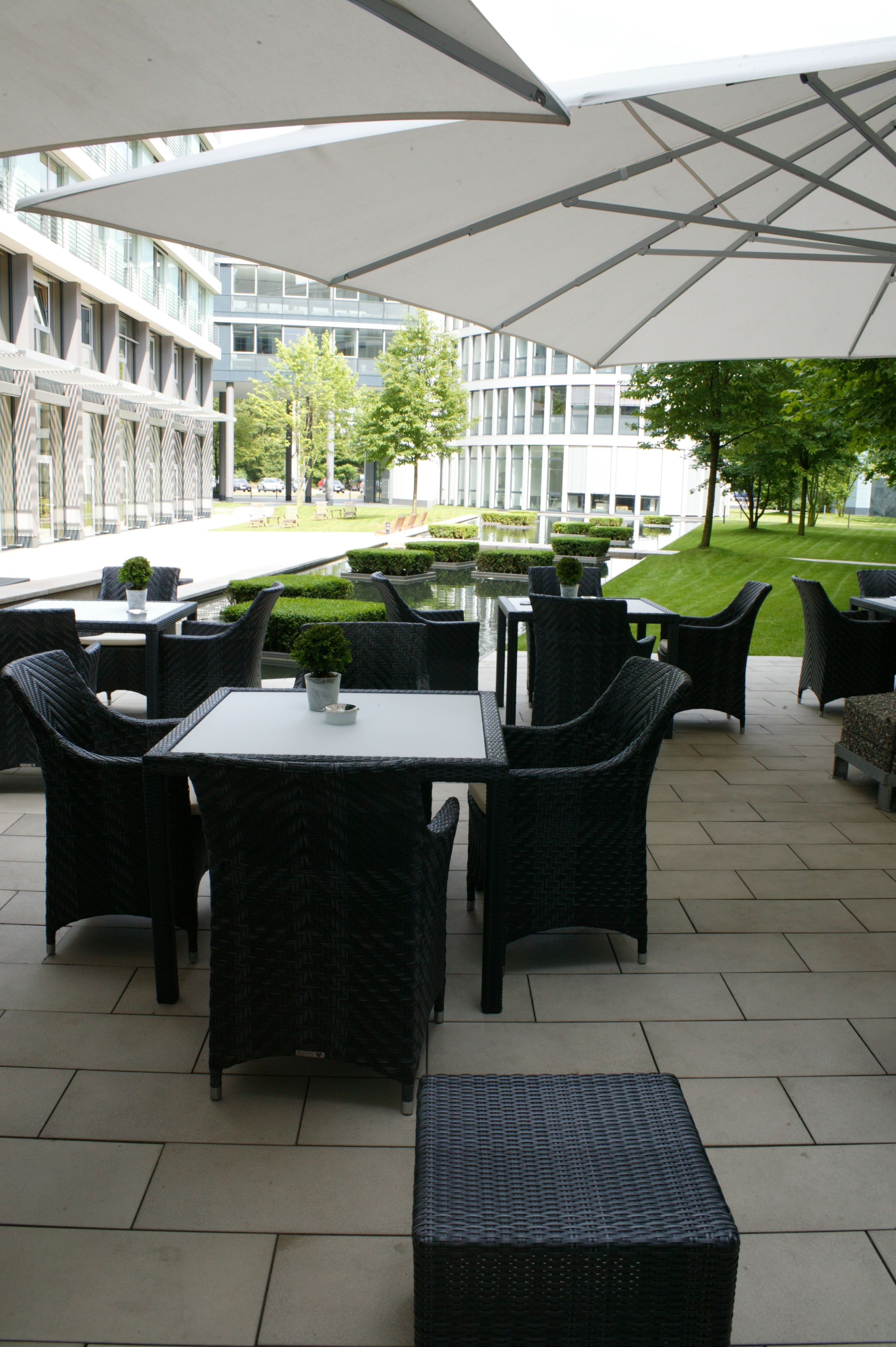 An outdoor patio area with wicker furniture, tables, and umbrellas.