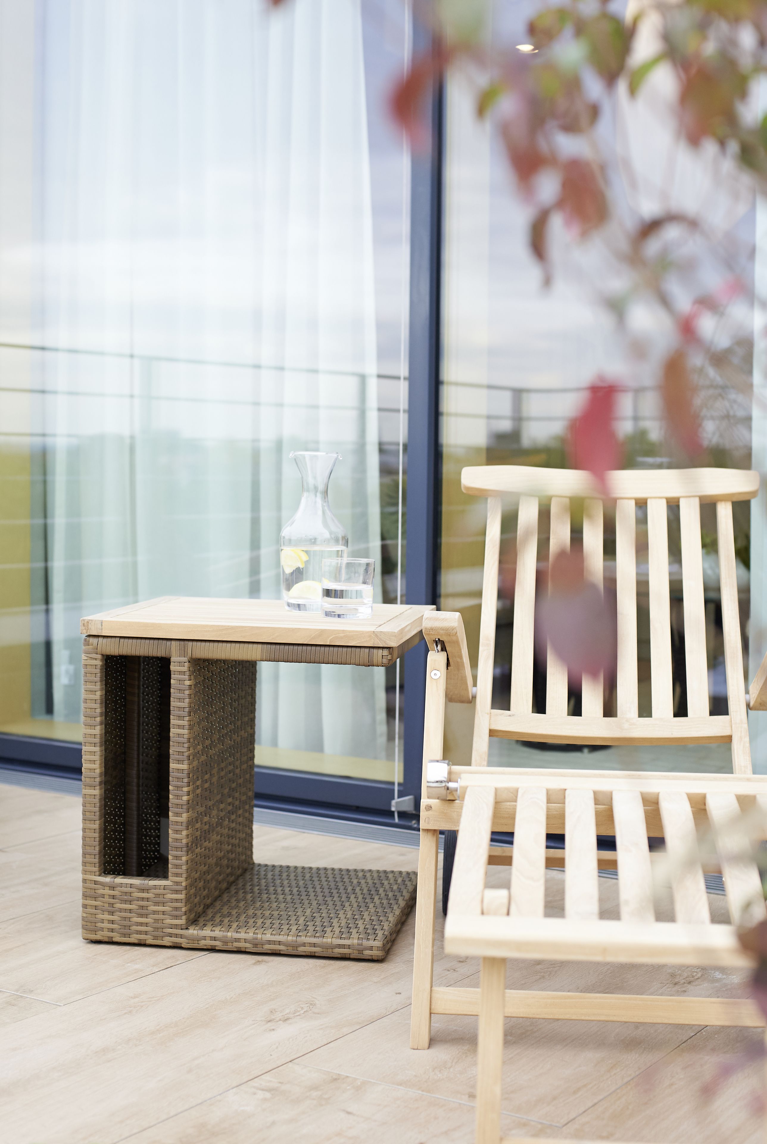 A wicker pet bed and a wooden chair in a room with a large window.