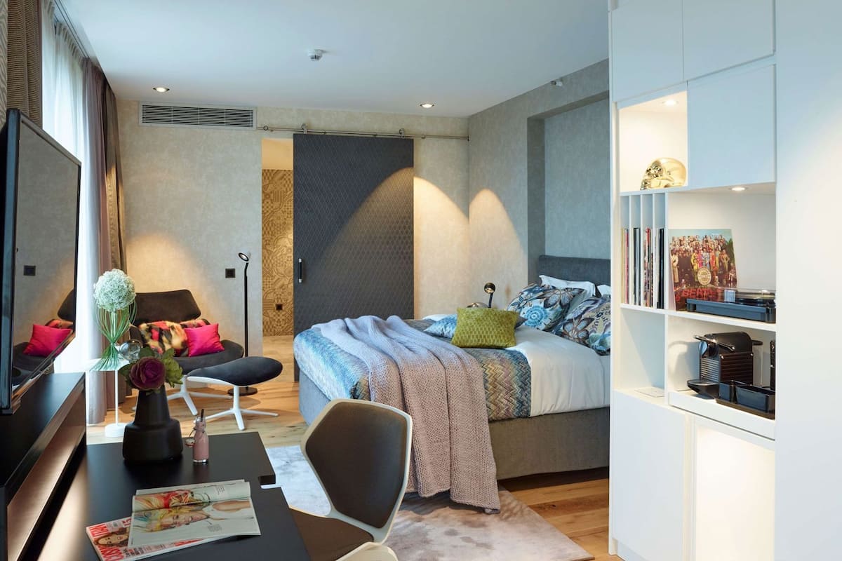 Ein modernes Schlafzimmer mit Bett, Nachttisch, Stuhl und Bücherregal.