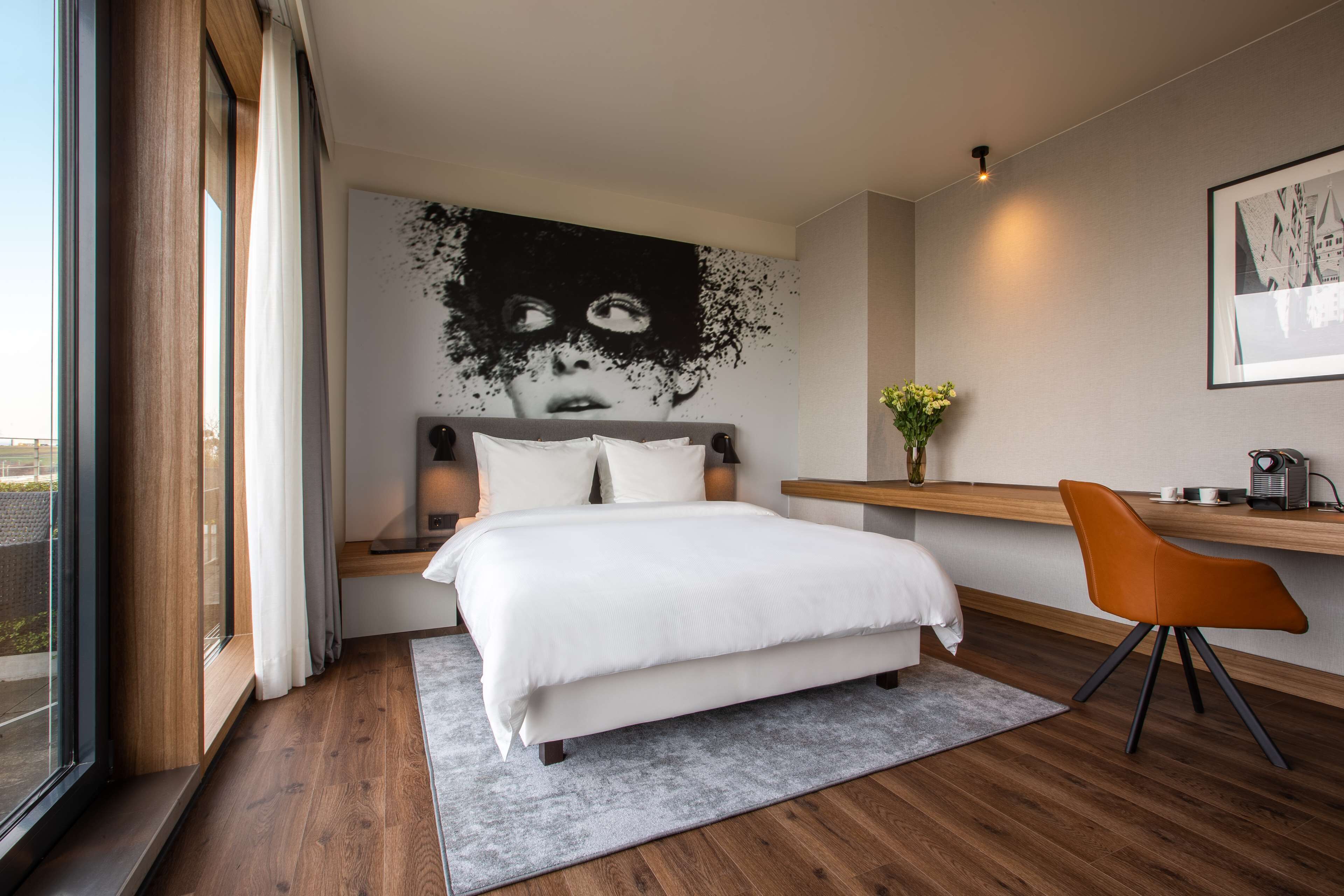 Een moderne slaapkamer met een groot bed, een bureau en een raam.