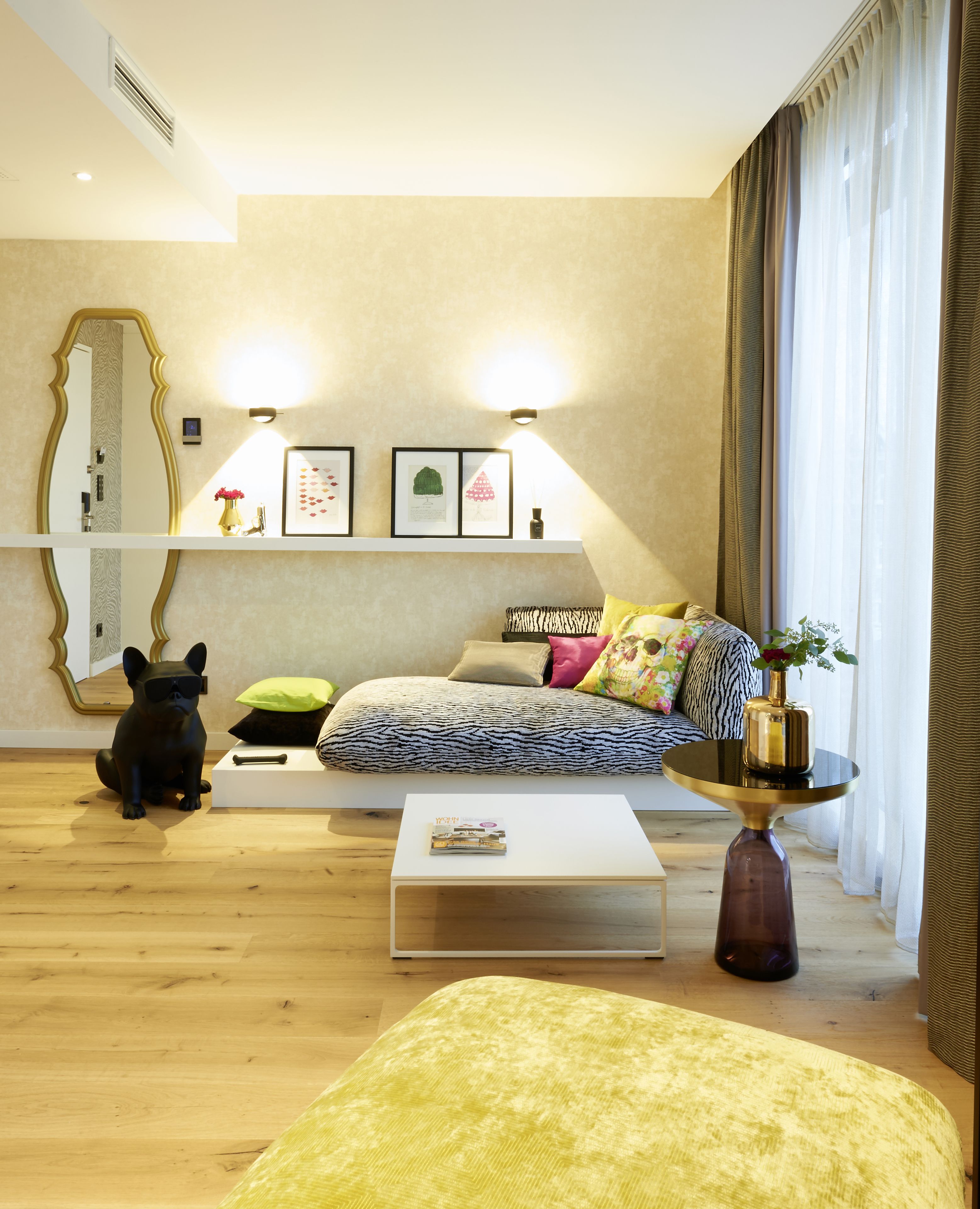 A modern living room with a sofa, a coffee table, a dog figurine, and a mirror.