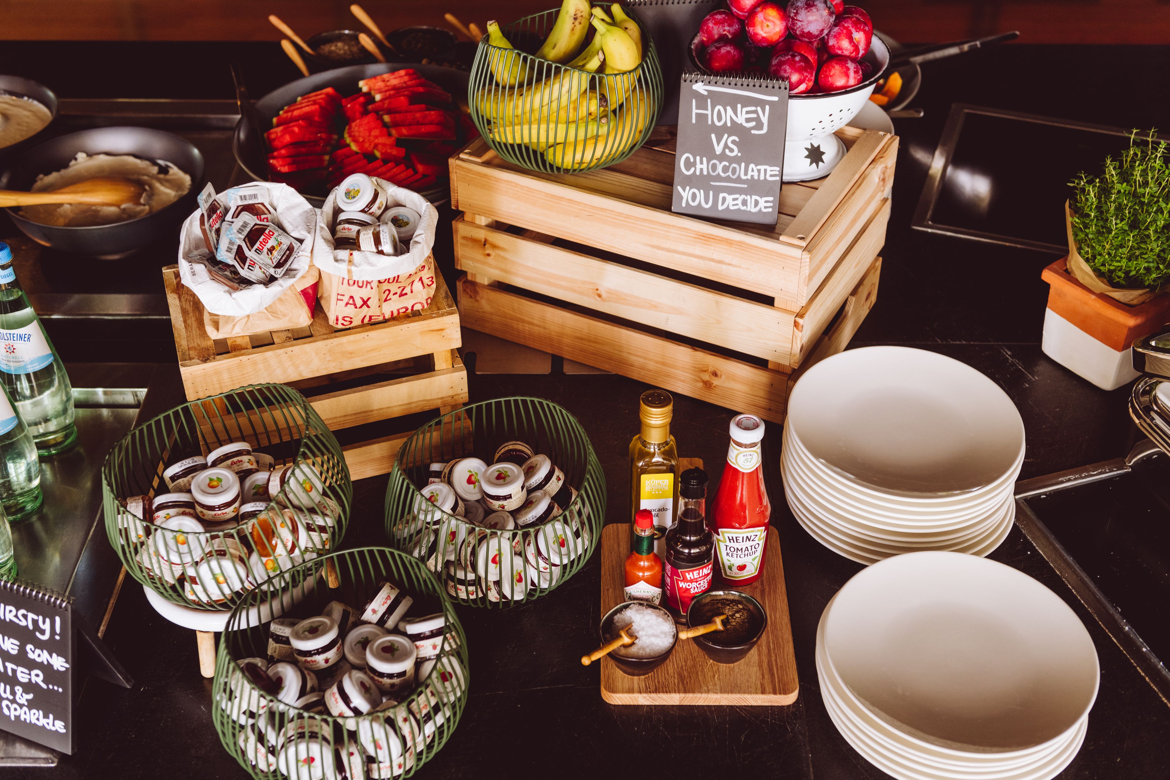 Un tavolo del buffet con diversi cibi, tra cui ciambelle, frutta e salse.