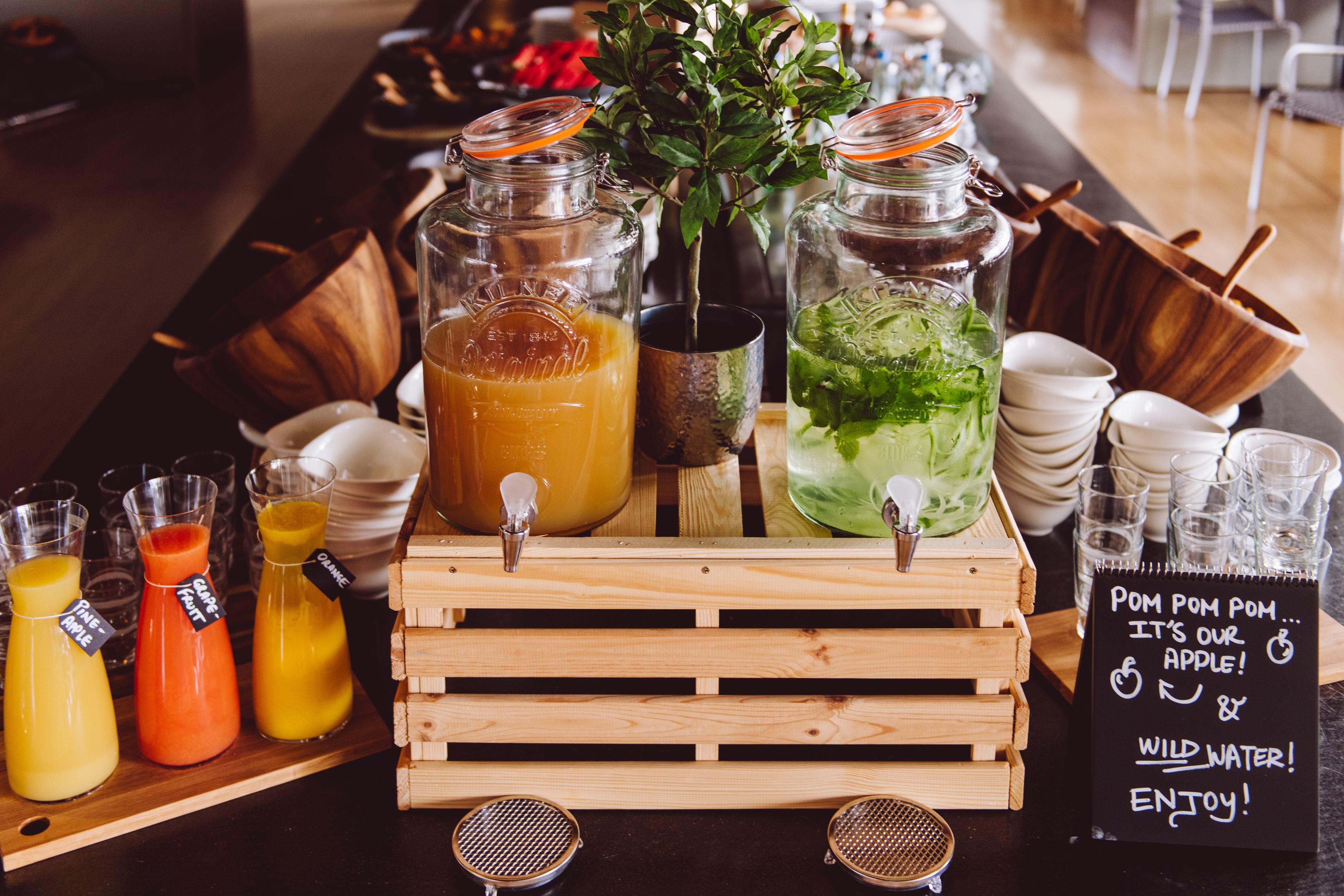 A beverage station with various drinks and a sign indicating apple juice and wild water.