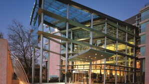 A modern building with a glass facade, a covered entrance, and a visible restaurant area inside.
