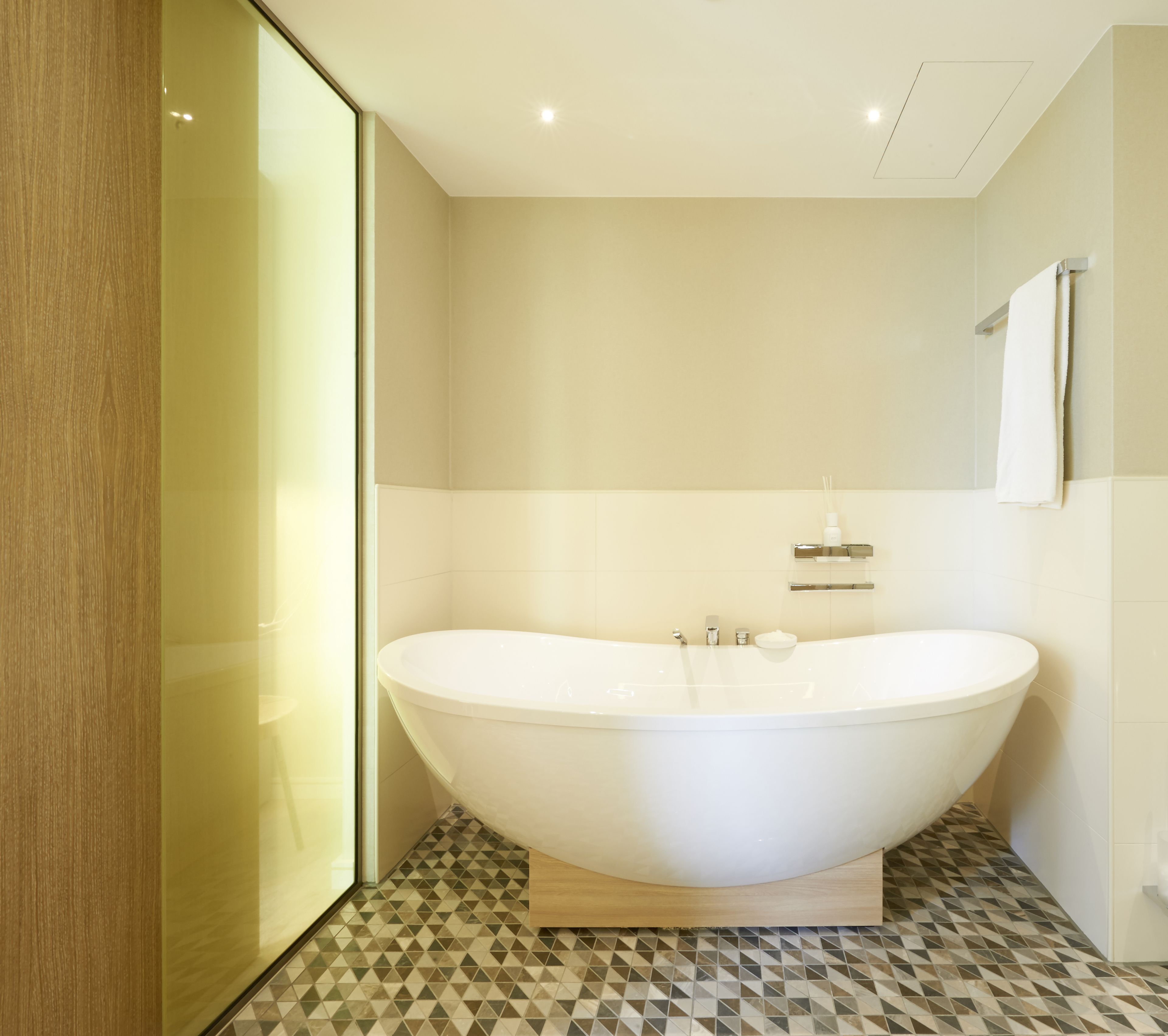 Une salle de bain moderne avec une baignoire sur pieds, une douche à parois de verre et un sol carrelé.
