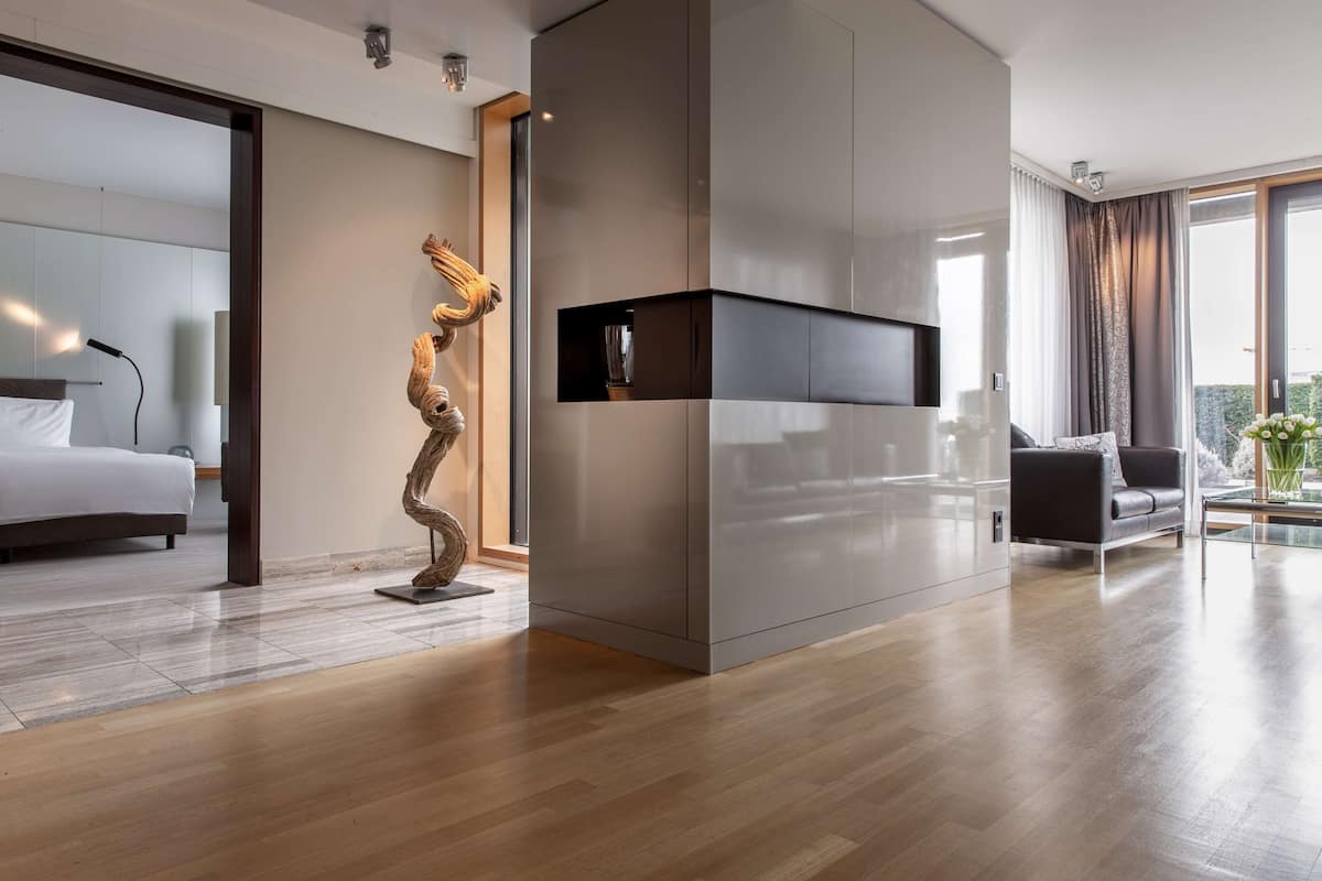 Ein modernes Hotelzimmer mit einem großen Bett, einer einzigartigen Skulptur, einem integrierten Fernseher und einem Balkon mit Blick.