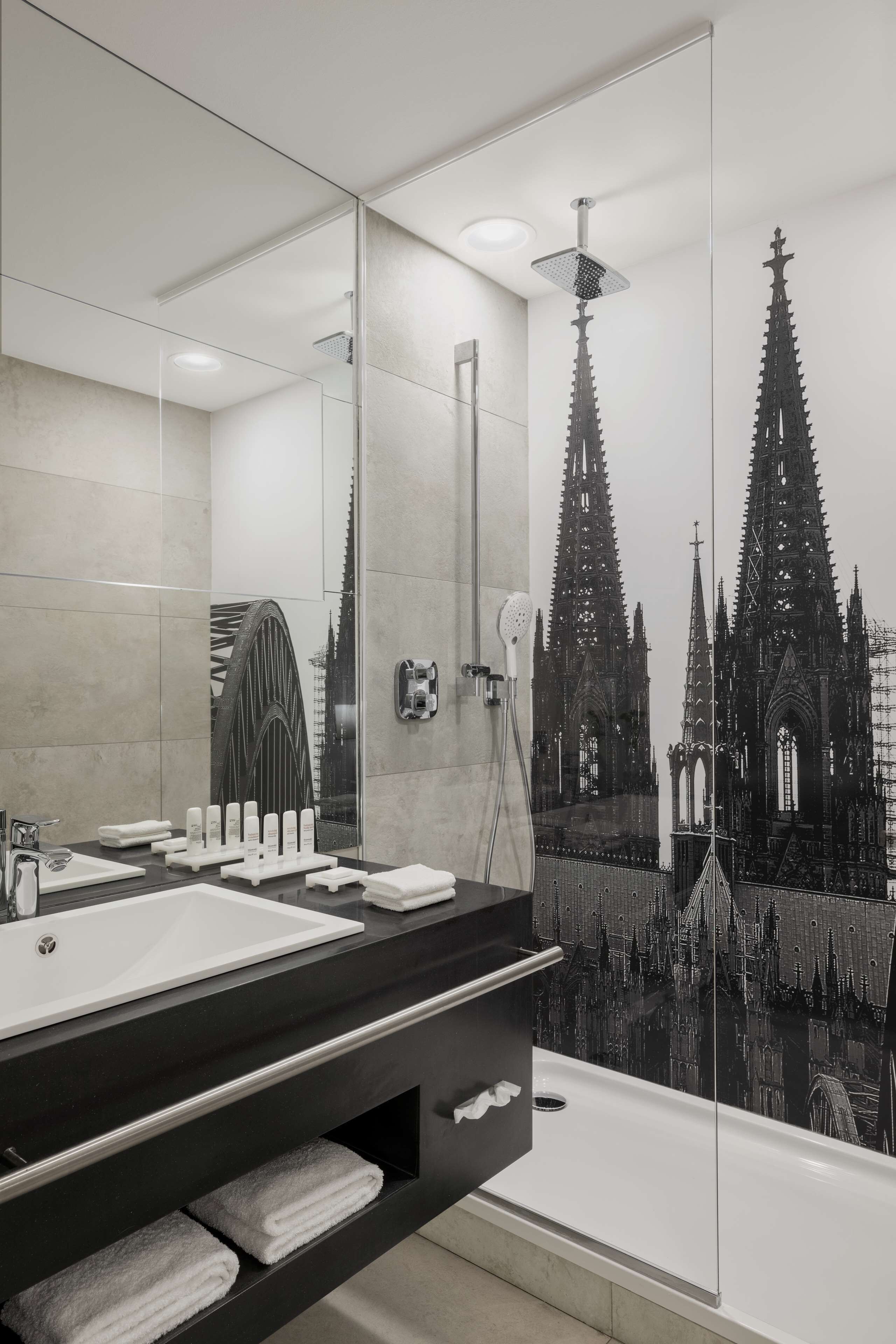 A modern bathroom with a large mirror, a bathtub, and a shower.
