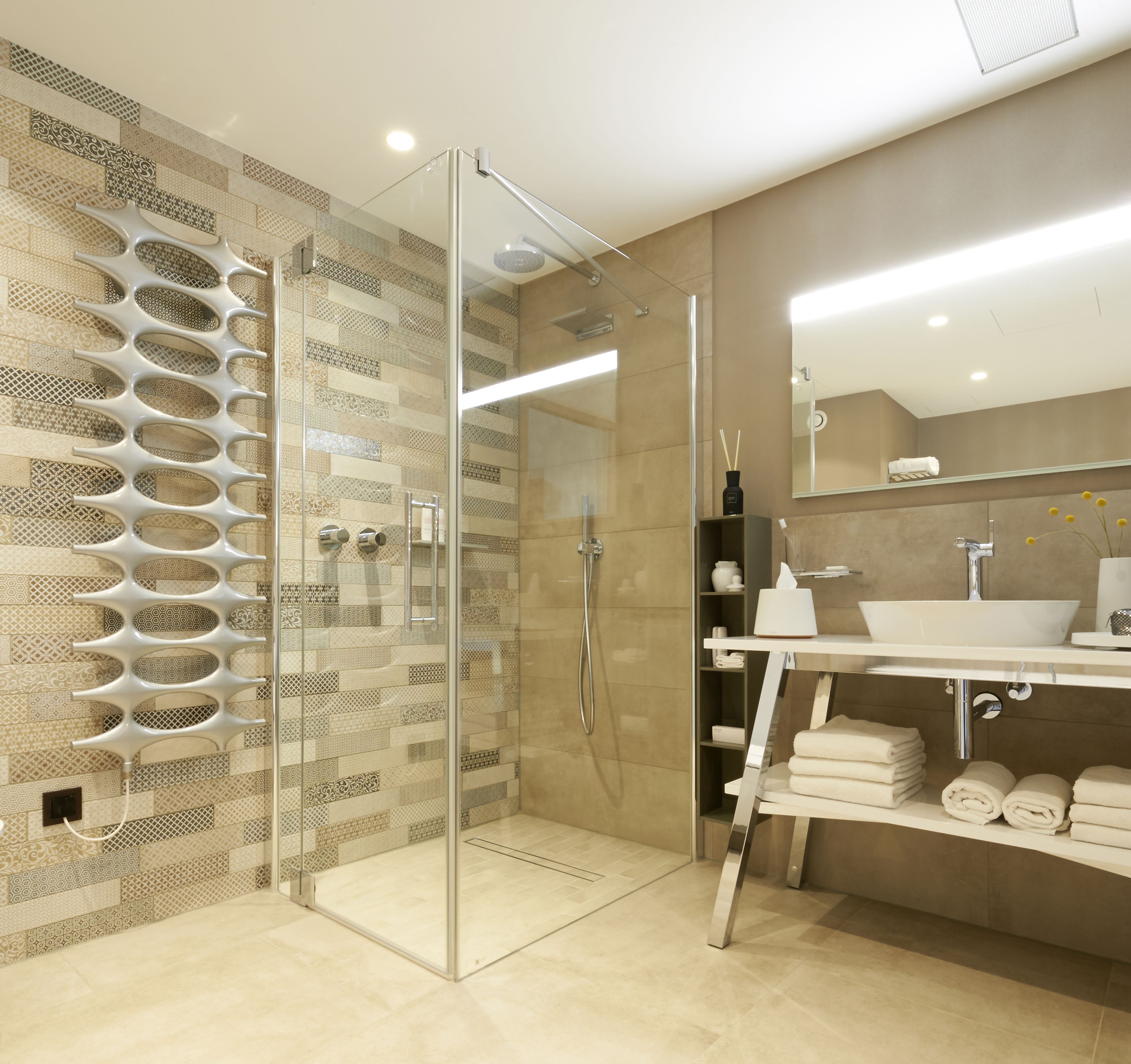 A modern bathroom with a glass shower enclosure, a large mirror, and a vanity with a sink and towel storage.