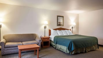 Une chambre d’hôtel comprenant un lit, un canapé, une table de chevet et deux lampes fixées au mur.