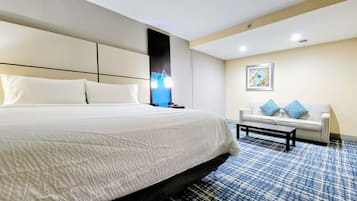 Habitación de hotel con una cama grande, un sofá, una mesita de centro y una lámpara fijada a la pared.