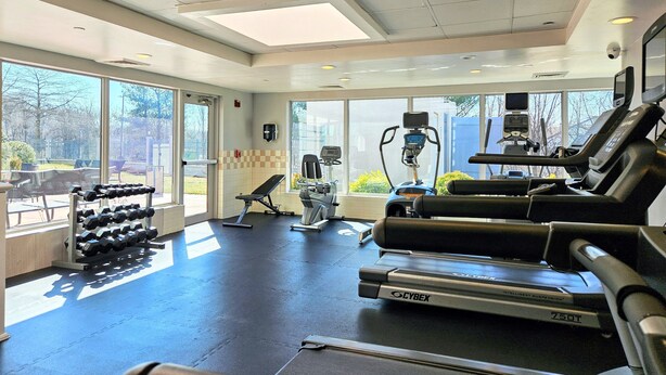 Un gimnasio con cintas de correr, mancuernas y equipo de ejercicio.