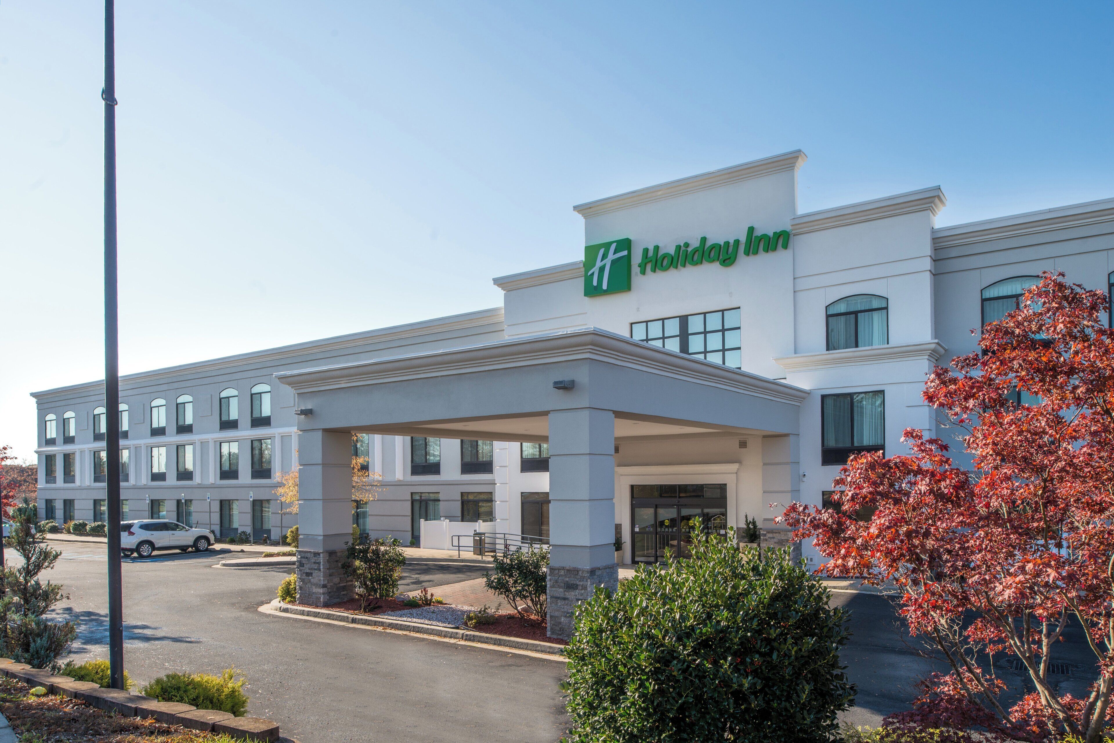 A Holiday Inn hotel with a covered entrance, multiple windows, and a parking lot.