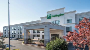 A Holiday Inn hotel with a covered entrance, multiple windows, and a parking lot.