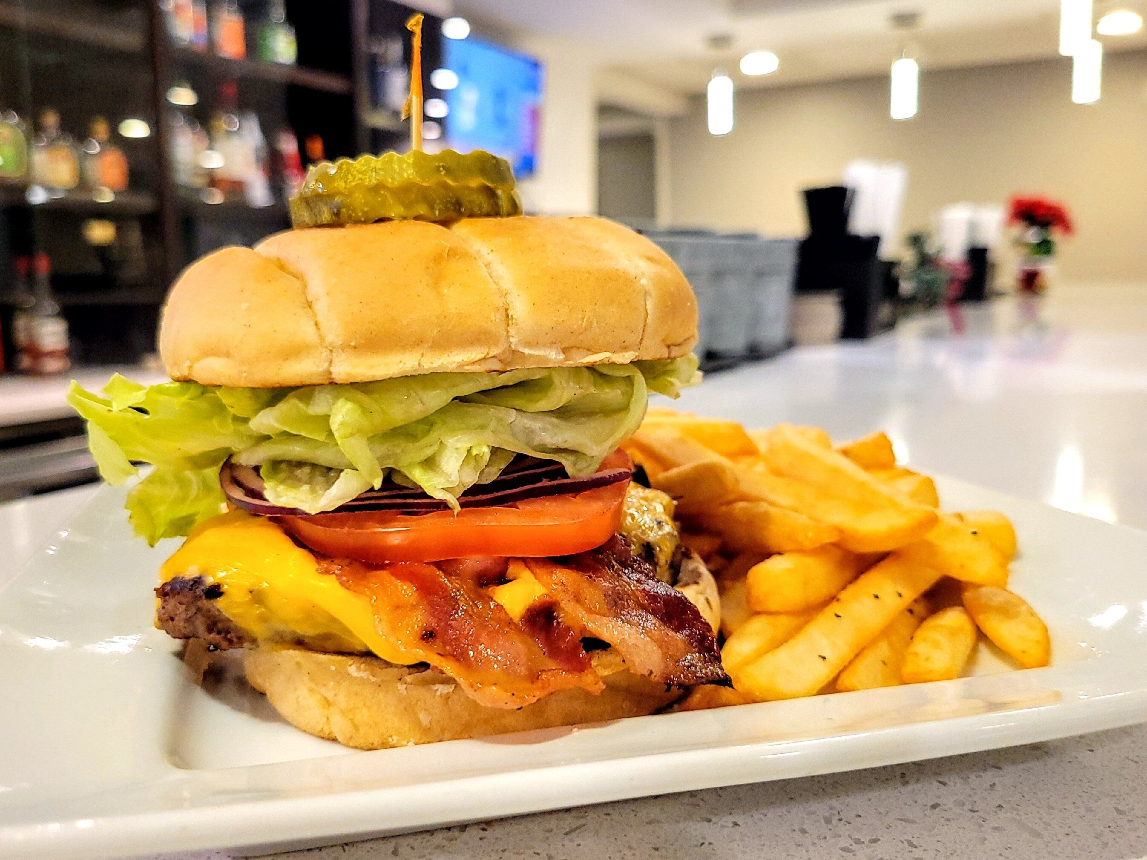 Une assiette avec un hamburger, des frites et un cornichon.
