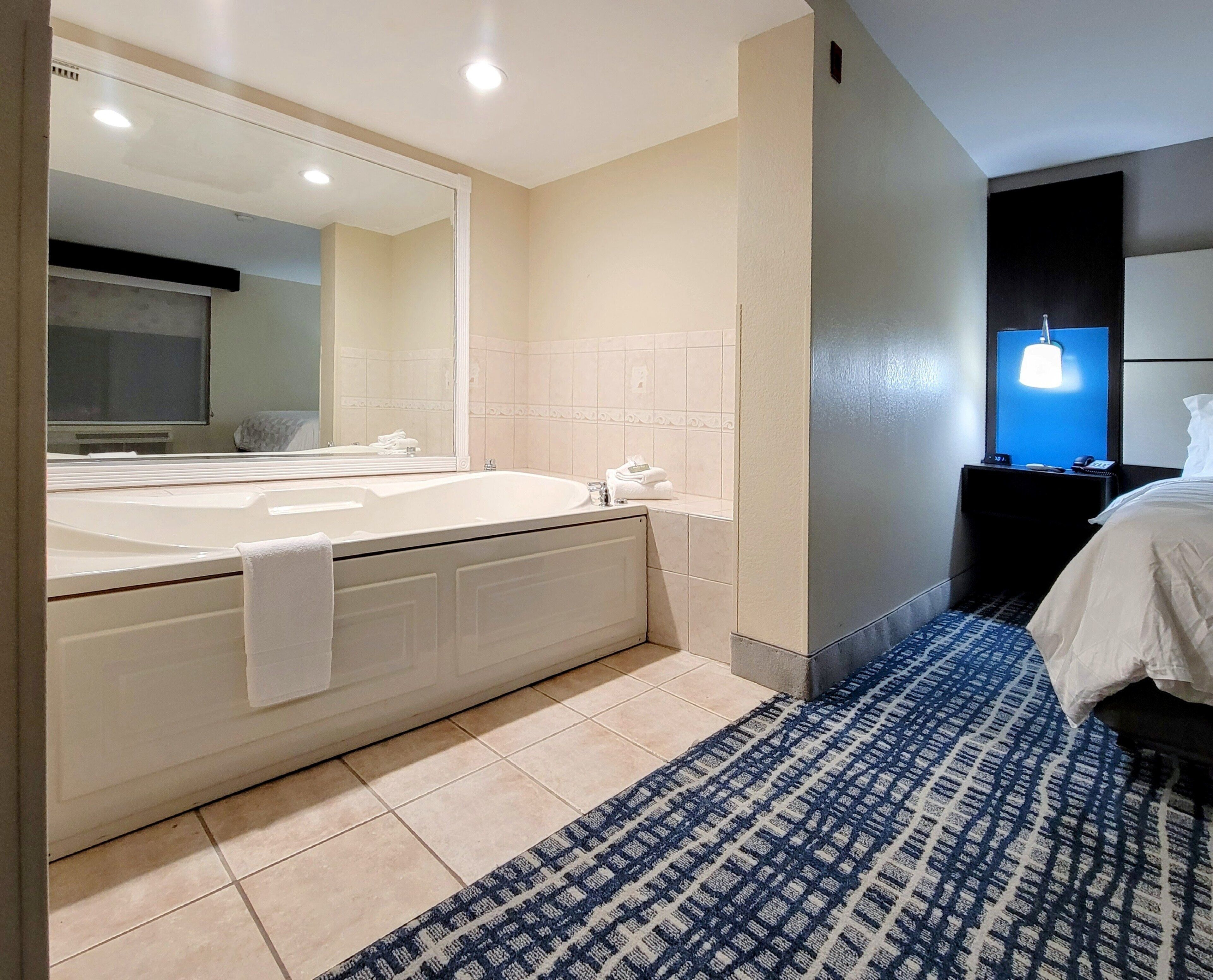 Un baño moderno con una bañera grande, un espejo y una zona de ducha separada.