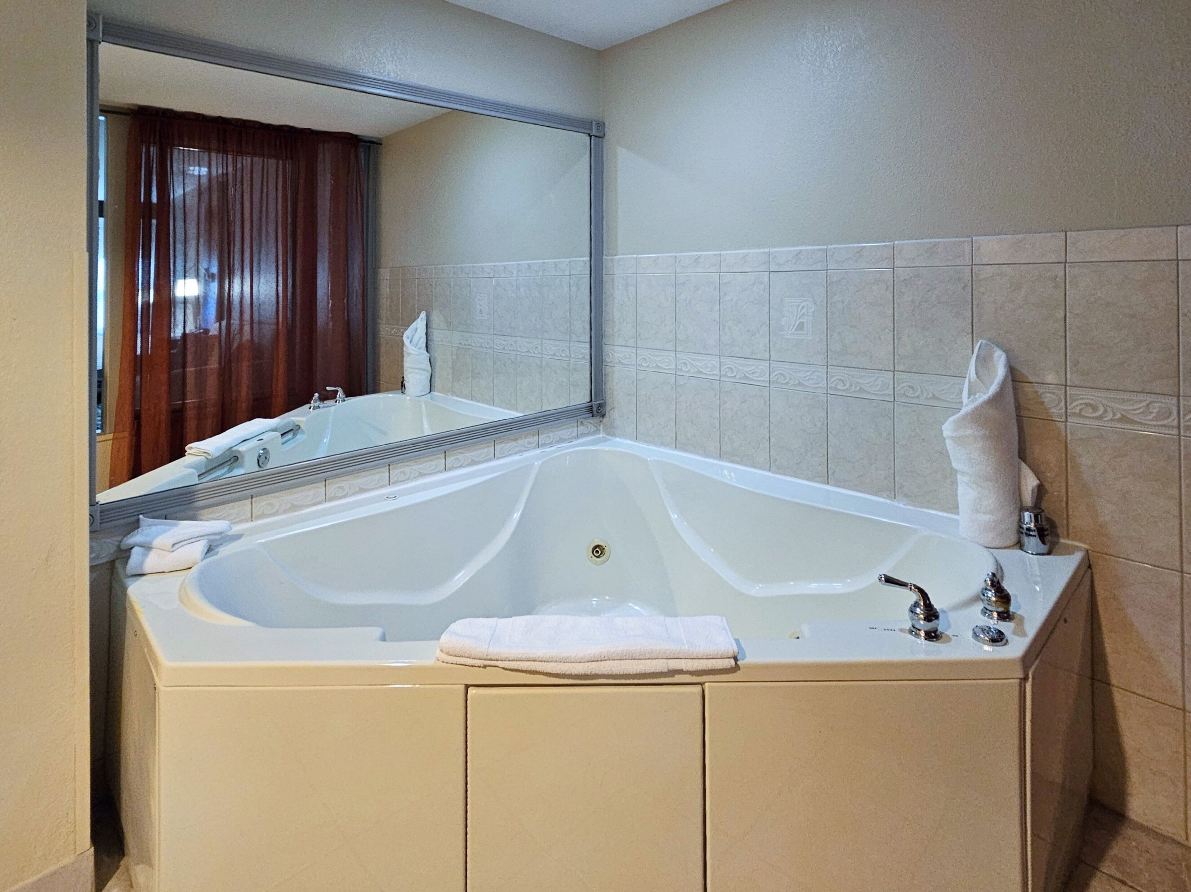 A large bathtub with a mirror above it, a sink, and a towel on the side.