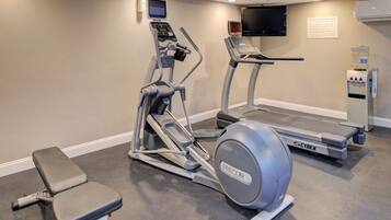 Un gimnasio con cintas de correr, una elíptica y una banca.