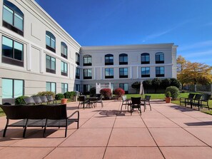 A courtyard with outdoor seating, a building with multiple windows, and a clear blue sky. - Holiday Inn Belcamp - Aberdeen Area by IHG (Belcamp)