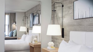 Una habitación de hotel con una cama grande, dos mesitas de noche con lámparas, un espejo y una obra de arte colgada en la pared.