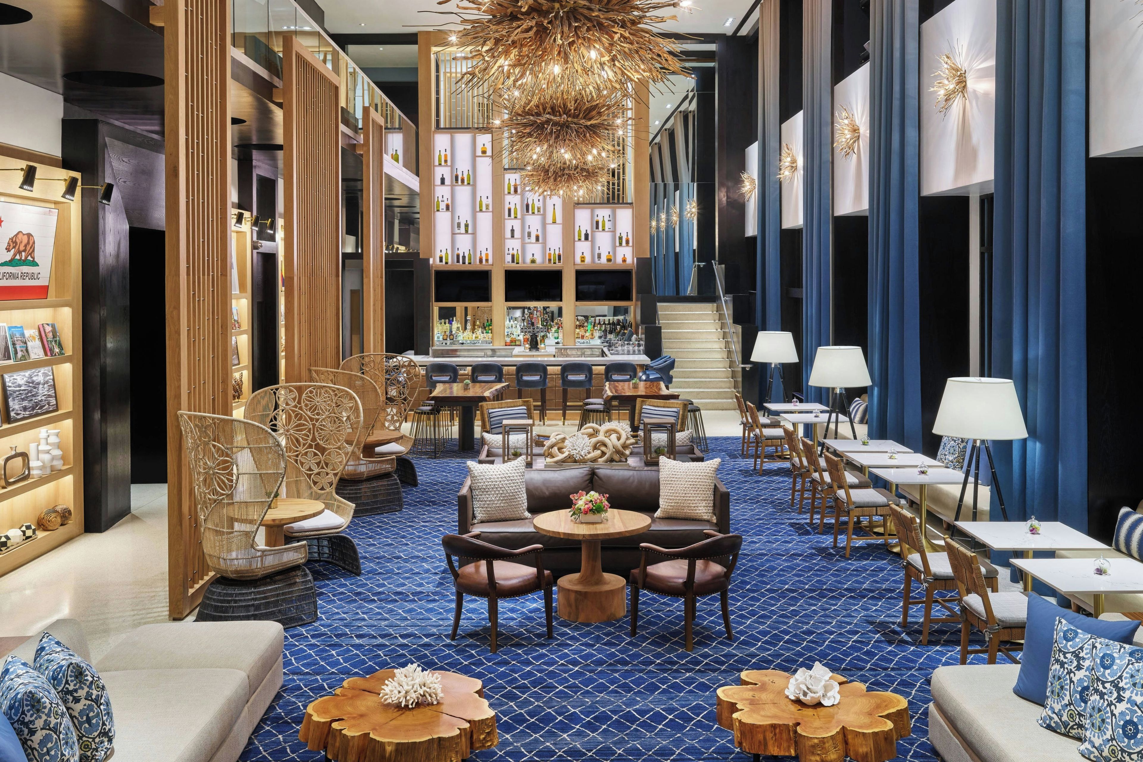 A hotel lobby with a bar area, seating arrangements, and a staircase.