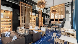 Un moderno vestíbulo de hotel con una zona de estar, un bar y una escalera.