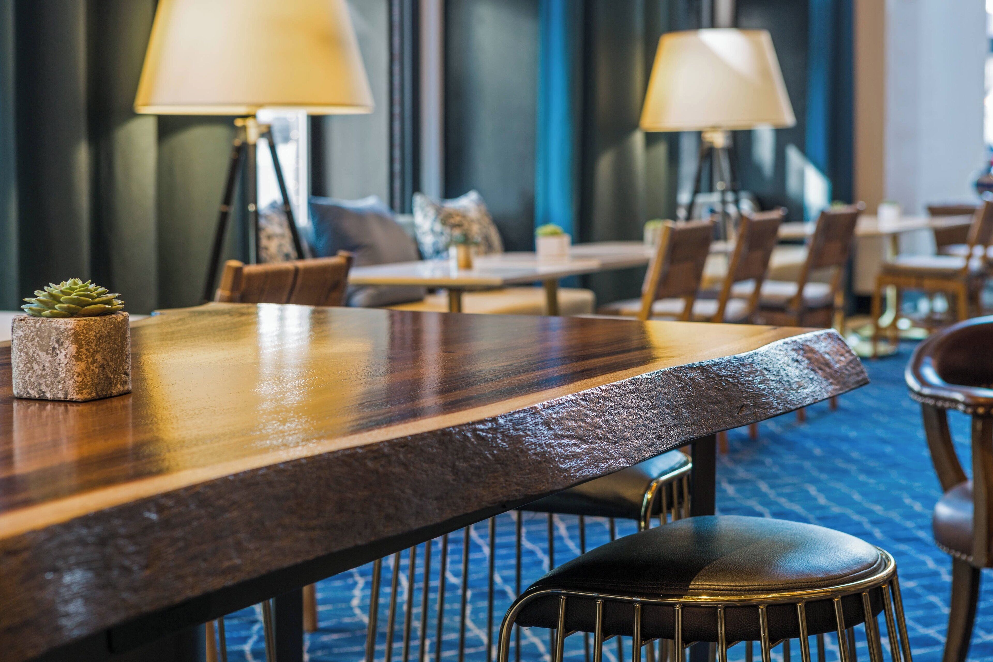 A hotel dining area with wooden tables, chairs, and lamps.