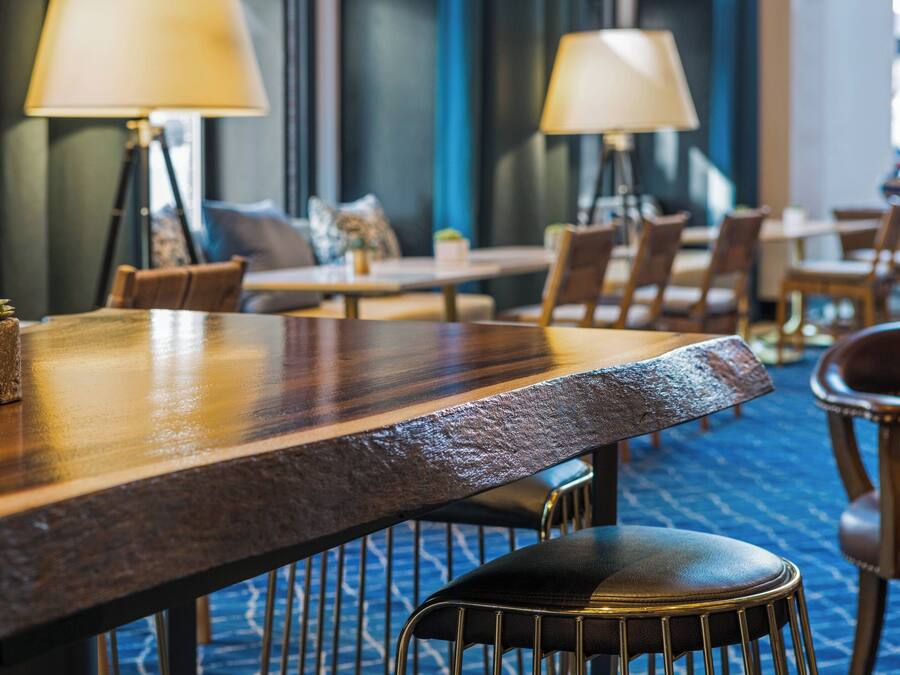 A hotel dining area with wooden tables, chairs, and lamps.