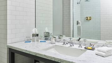 A bathroom with white tiled walls, a marble sink, and a large mirror.