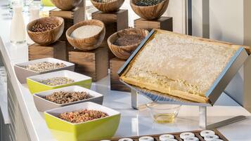 A buffet with various food items in wooden and green bowls, a honeycomb display, and a tray of cookies.