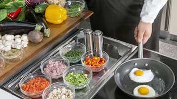 Una encimera de cocina con diversos ingredientes y una sartén con dos huevos que se cocinan.