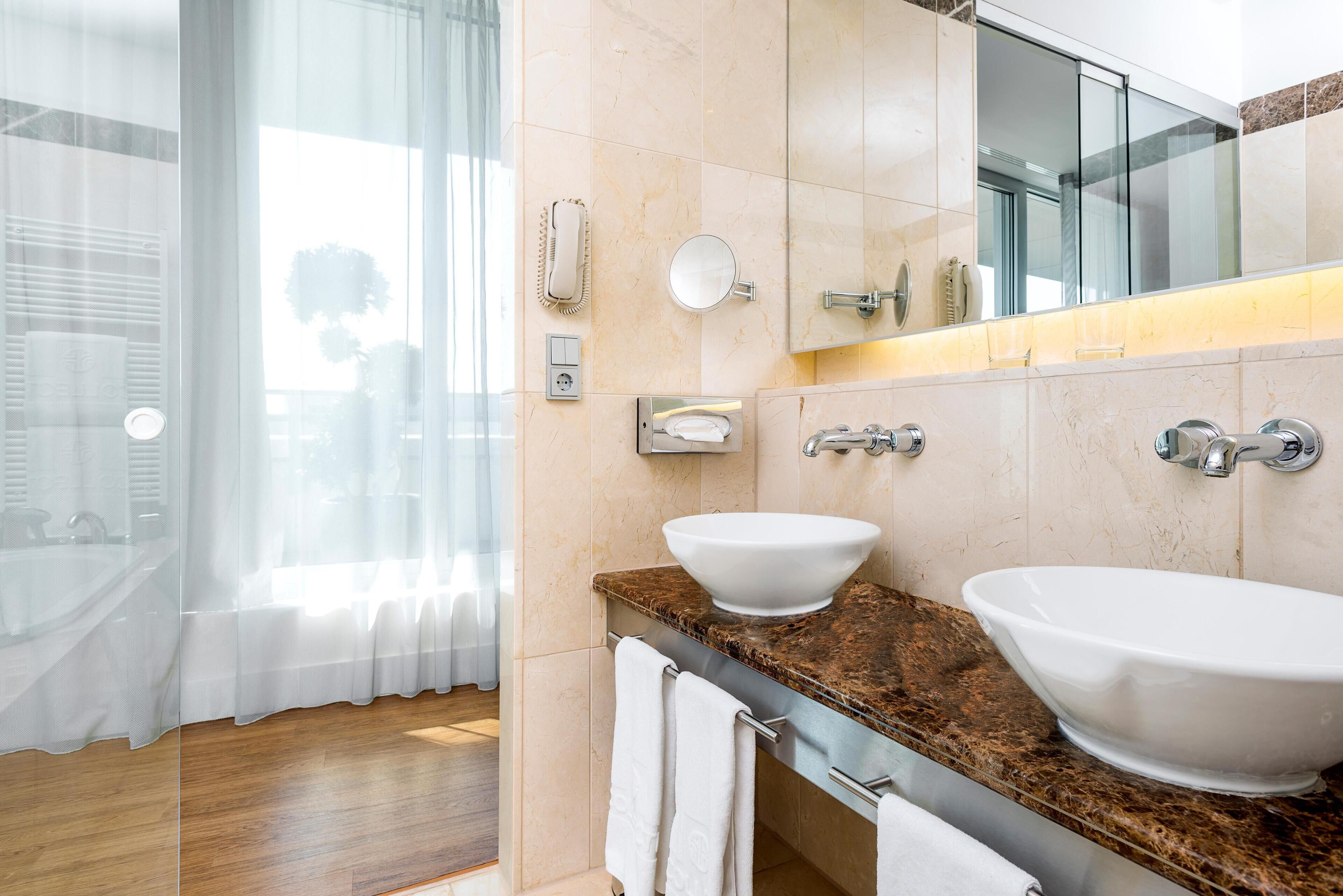 A modern bathroom with two sinks, a large mirror, and a glass shower enclosure.