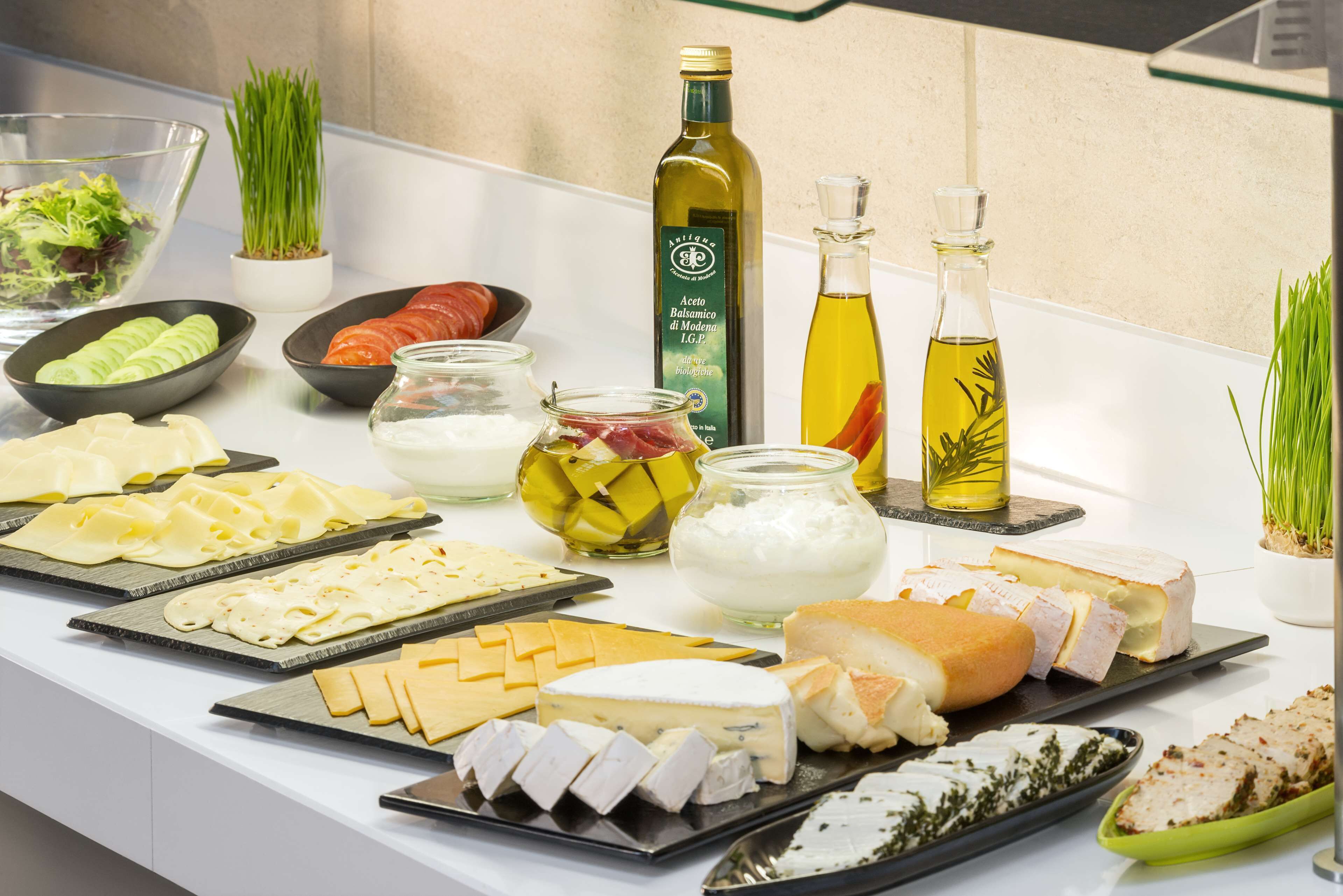 A buffet table with various cheeses, meats, and condiments.