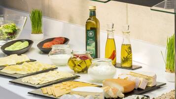 A buffet table with various cheeses, meats, and condiments.