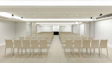 Een congrescentrum met rijen stoelen gericht op een zwart podium.
